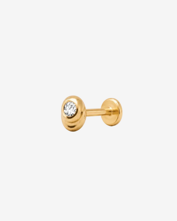 Gold stud earring with a central gemstone on a light gray background